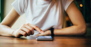 A woman searches on her smartphone as it rests on a table.